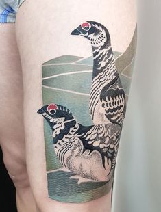 two birds sitting on top of each other in front of a woman's thigh