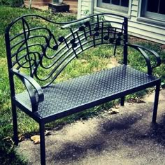 a metal bench sitting in the grass near a house