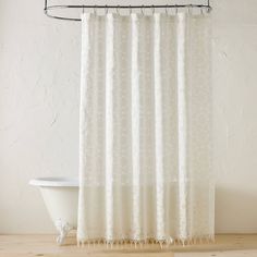 a white shower curtain hanging over a bath tub