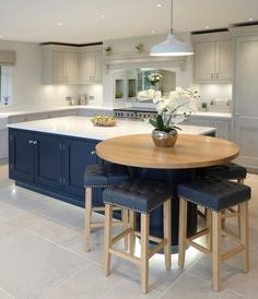 a kitchen with two stools and a table in the middle of it, next to an island