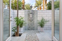 an outdoor shower surrounded by palm trees and other greenery is featured in this magazine