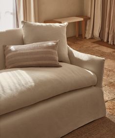 a white couch with pillows on it in front of a window