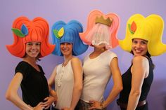 three women wearing wigs standing next to each other in front of a purple wall