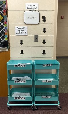 three blue plastic bins are stacked on wheels in front of a bulletin board with words and arrows