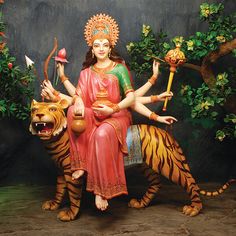 a statue of a woman sitting on top of a tiger next to a small animal