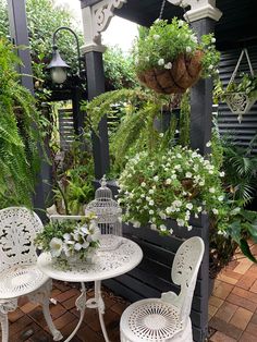 two white chairs sitting on top of a brick floor next to a table and chair