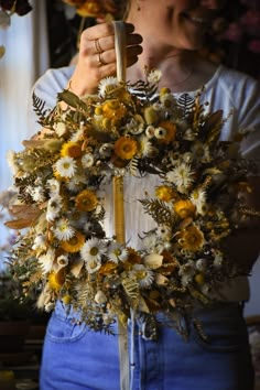 a woman is holding a wreath with flowers on it