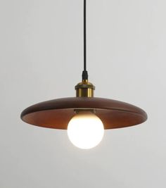 a light hanging from a ceiling with a white wall behind it and a black cord