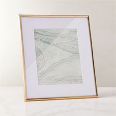 a white and gold frame on a table with a painting in it's center