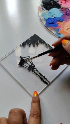 a woman is using scissors to cut out an art piece with acrylic paint