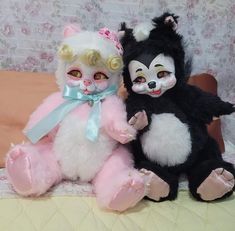 two stuffed animals sitting next to each other on a bed