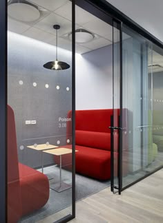 an office with glass walls and red couches