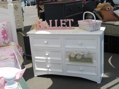 a white dresser sitting next to a bed in a room with other furniture and accessories