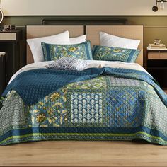 a bed with blue and green bedspread in a bedroom next to a night stand