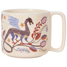 a ceramic mug with a dragon on it's side and flowers around the edges