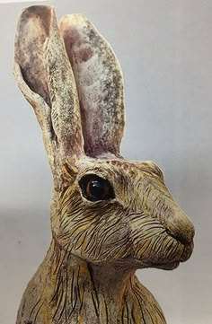 a close up of a statue of a rabbit on a white surface with grey background