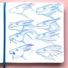 an open notebook with drawings of different types of dinosaurs on it and blue pencils