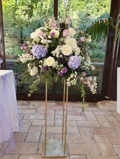 a vase filled with purple and white flowers sitting on top of a table next to a window