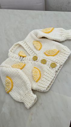 a knitted sweater with lemons on it sitting on top of a marble table