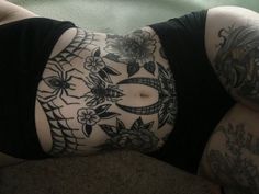 a woman with tattoos on her stomach laying down