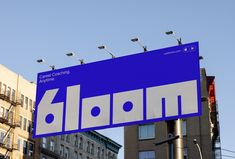 a blue and white street sign hanging from the side of a pole in front of tall buildings