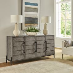 a living room scene with focus on the sideboard and two vases sitting on top