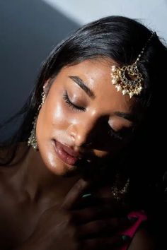 a woman with her eyes closed wearing gold jewelry