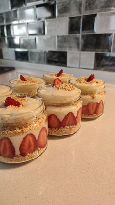 four desserts with strawberries are sitting on the counter