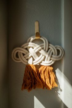 an orange tassel hanging on the wall next to a white knot and wooden hook