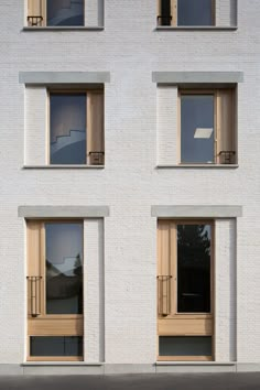 three windows on the side of a white building