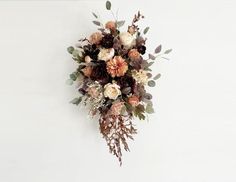 a bouquet of flowers is hanging on the wall in front of a white wall with no one around it