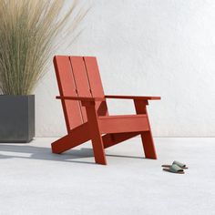 a red wooden chair sitting next to a potted plant