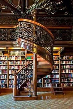 a spiral staircase in the middle of a library filled with books