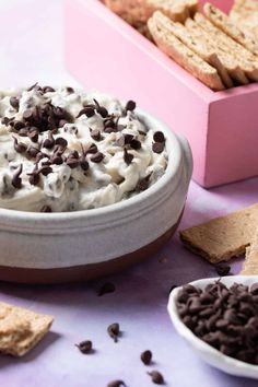 a bowl of ice cream with chocolate chips and crackers around it on a table