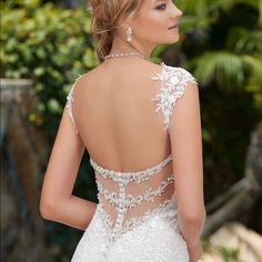 a woman in a white wedding dress with an open back and beading on it