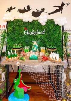 a table topped with lots of desserts and balloons in front of a green wall