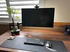 a computer desk with a keyboard, mouse and speakers on it in front of a large screen