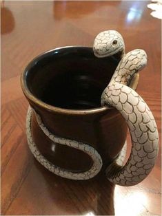 a ceramic snake in a coffee cup on a table