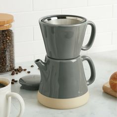 a coffee pot sitting on top of a counter next to a cup filled with coffee