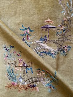 an embroidered fabric with flowers and birds in the background, on a beige ground cloth