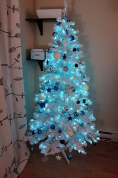 a white christmas tree with blue lights and ornaments