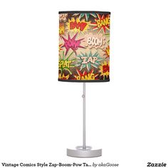 a lamp that is on top of a metal stand with a comic print shade over it