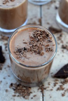 there is a chocolate drink with nuts in it on the table next to two cups