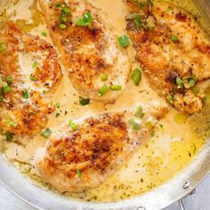 some chicken is cooking in a pan with green onions and sauce on the side,