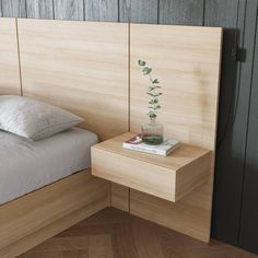 a bed sitting next to a nightstand with a book on it and a plant in a vase