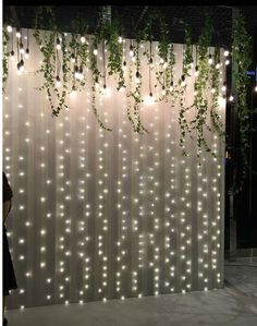 the curtain is decorated with white lights and greenery hanging from it's sides