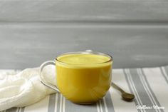 a glass cup filled with yellow liquid on top of a white and blue table cloth