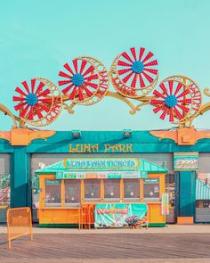 the carnival rides are brightly colored and have ferris wheels on top of them in front of a turquoise sky