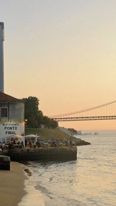 an image of people on the beach with a bridge in the background