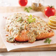 a piece of salmon covered in sauce and garnished with parsley on a cutting board